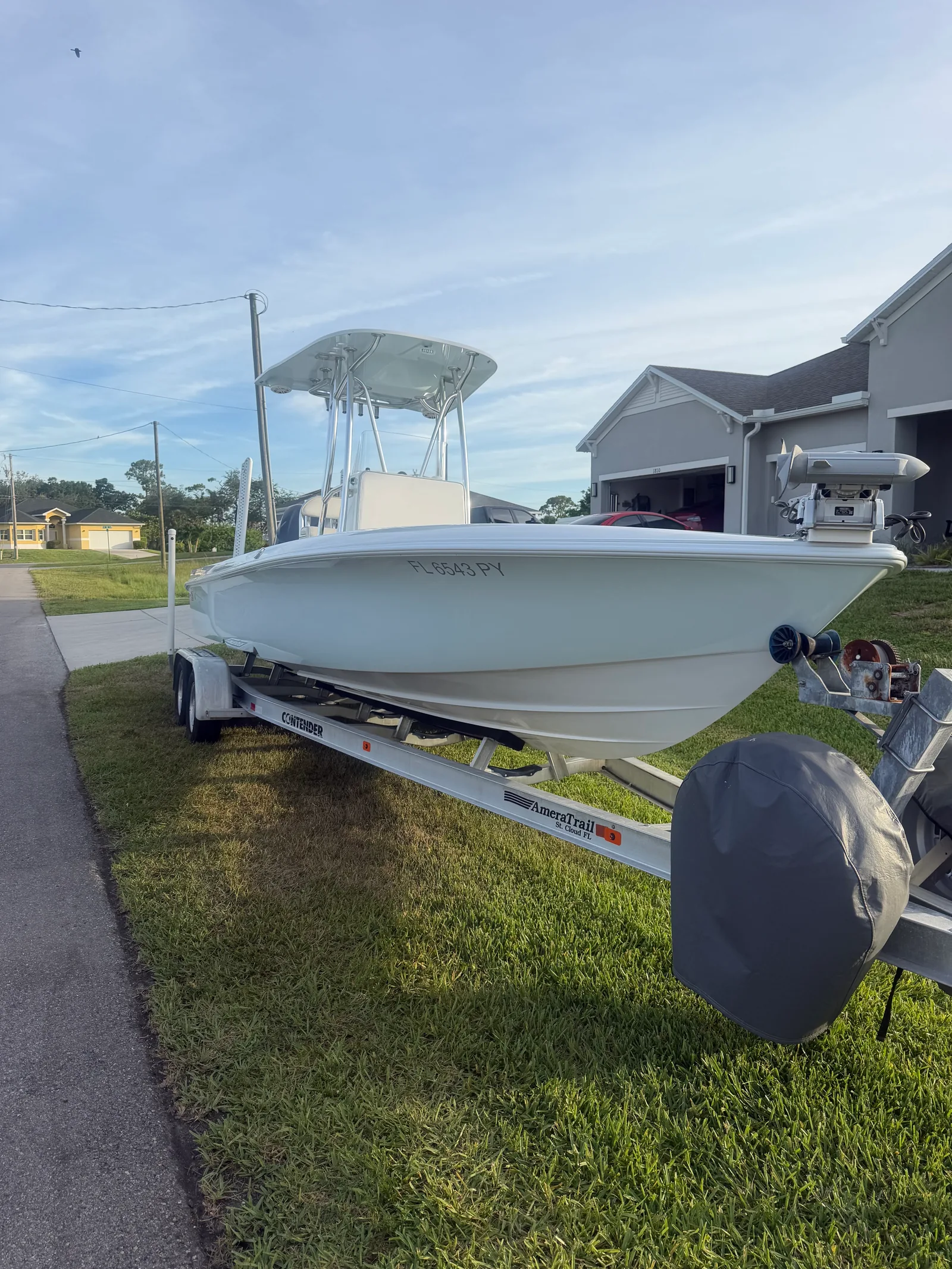 White center-console boat on a trailer beside a driveway