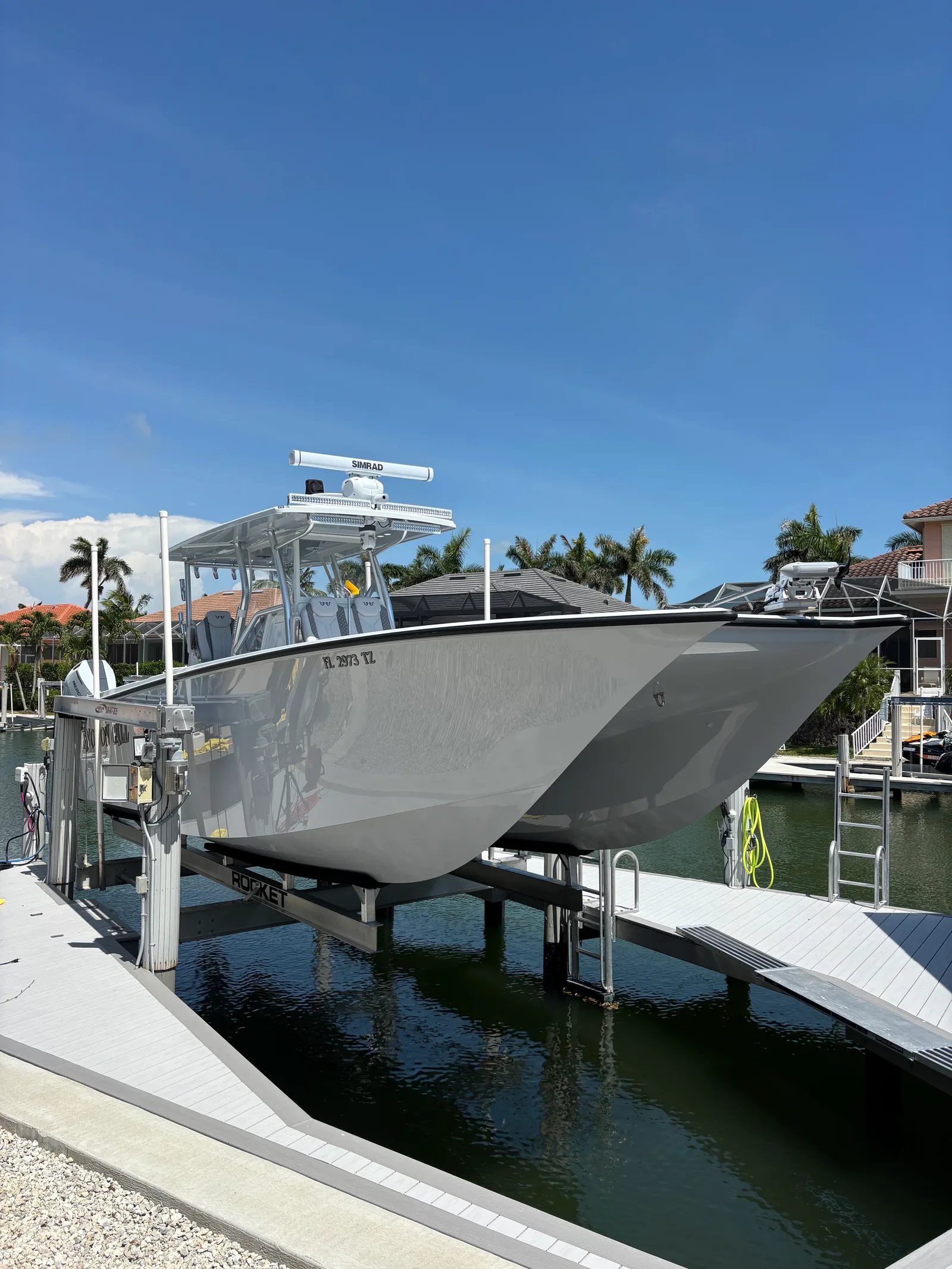 White twin-hull center-console boat on a canal-side lift